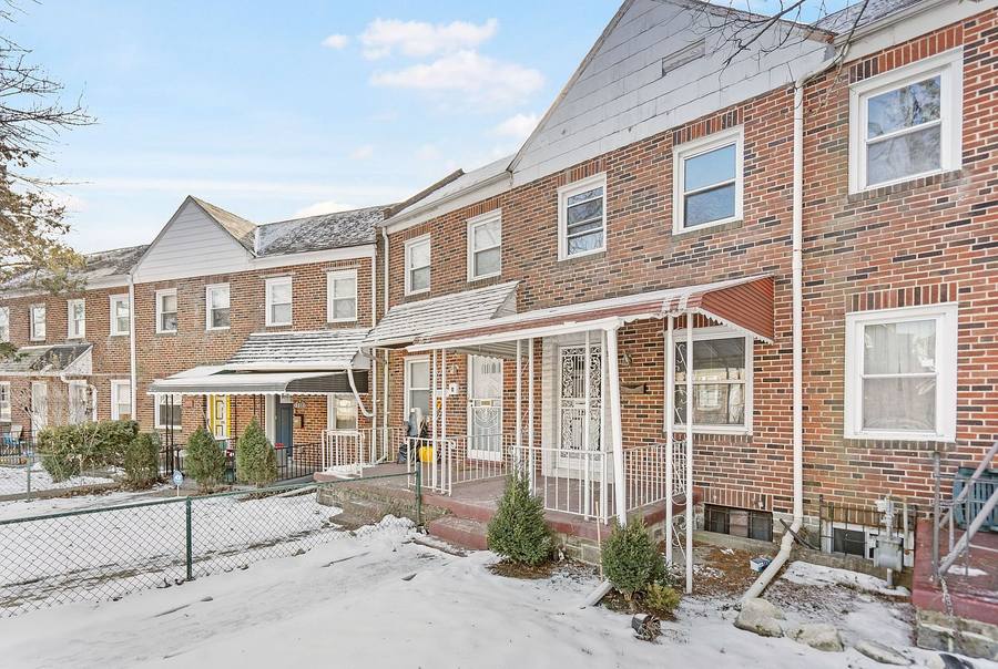 Brick townhomes on Elbert Street with covered front porches, photographed in winter