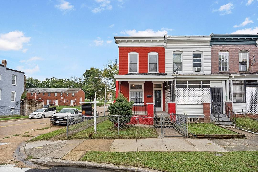 Red brick end-of-row townhouse at 945 N Ashburton St with a fenced front yard on a corner