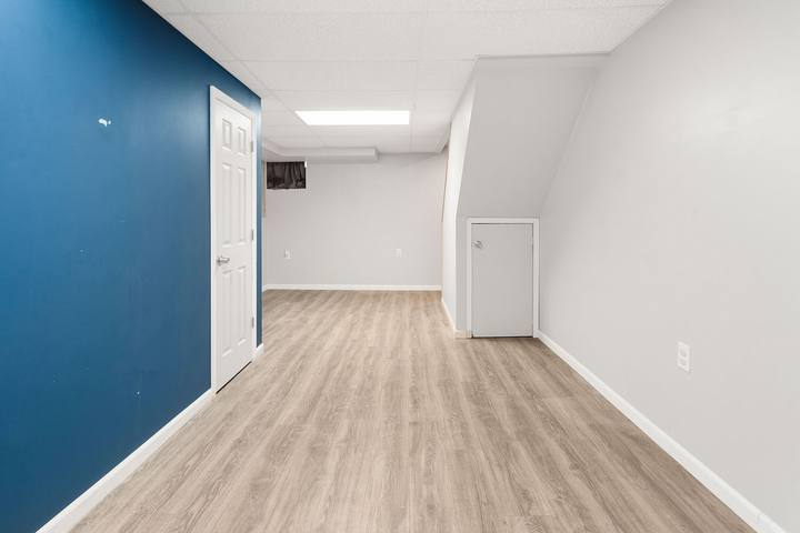 Finished basement with plank floors and a navy blue accent wall