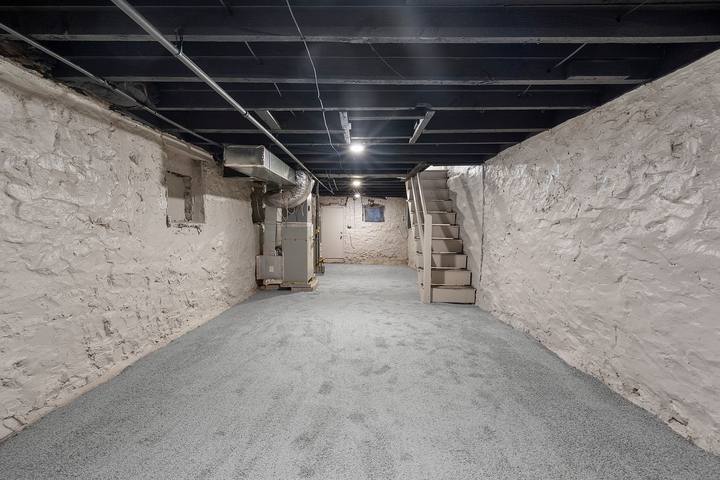 Basement with painted stone walls and a gray floor, used for storage