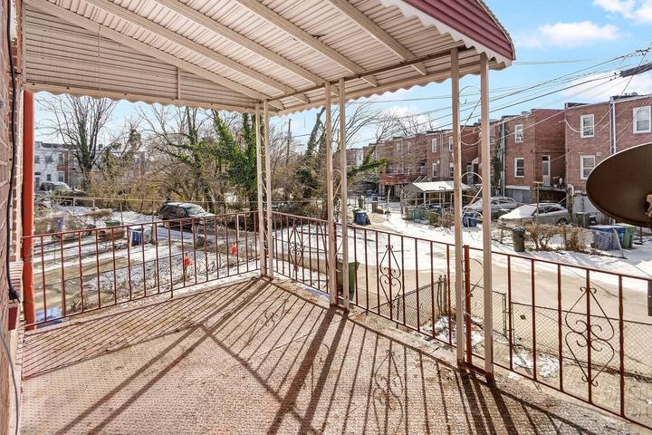 Covered balcony with an iron railing looking out over the street