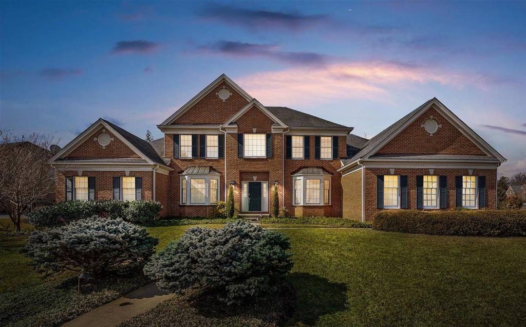 Brick colonial home with lit windows at dusk