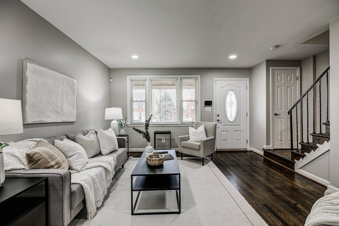 Staged living room with dark hardwood floors and a front staircase